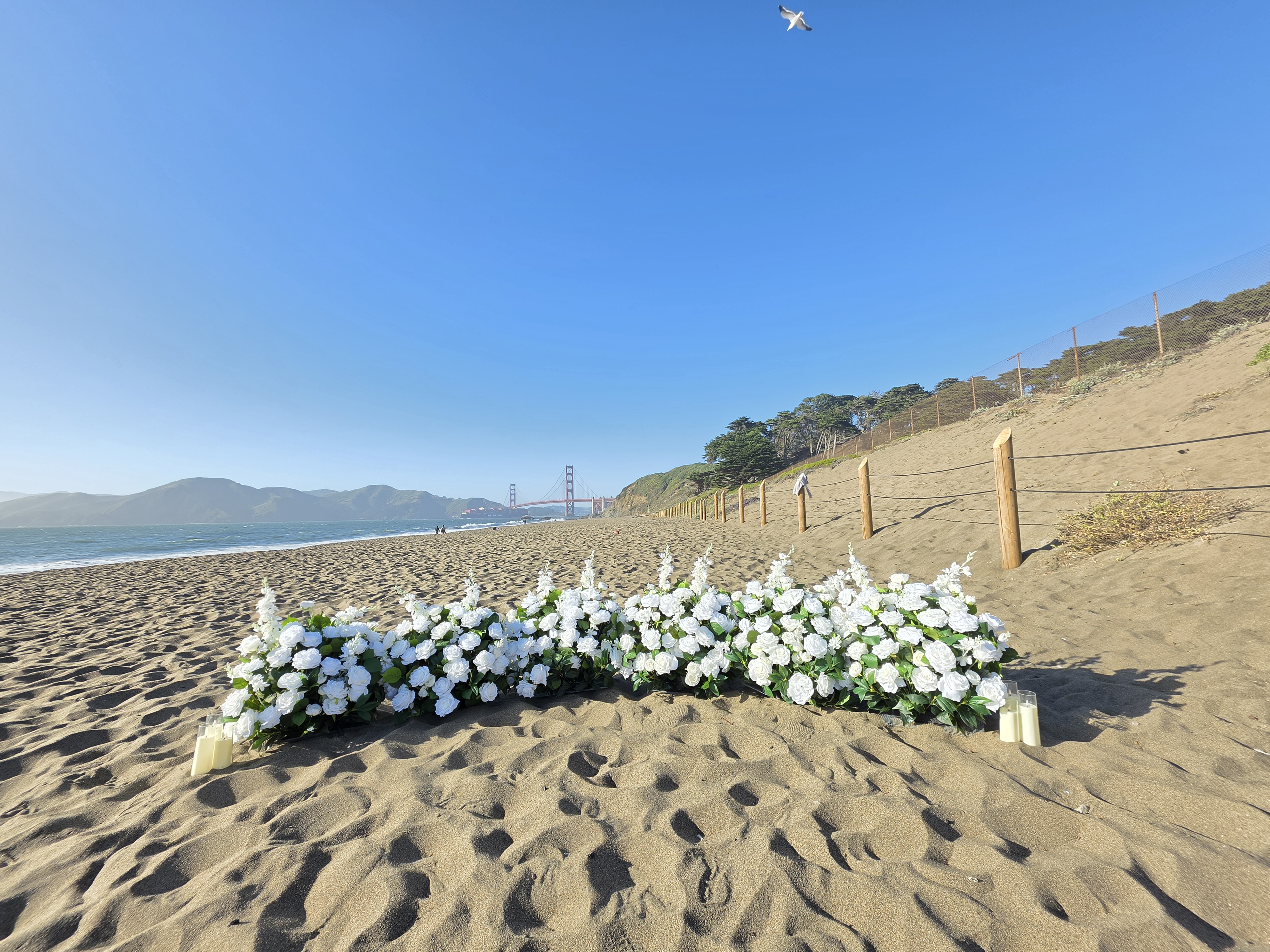 The Intimate Promise – white grounded floral proposal setup at Baker Beach, SF Bay Area