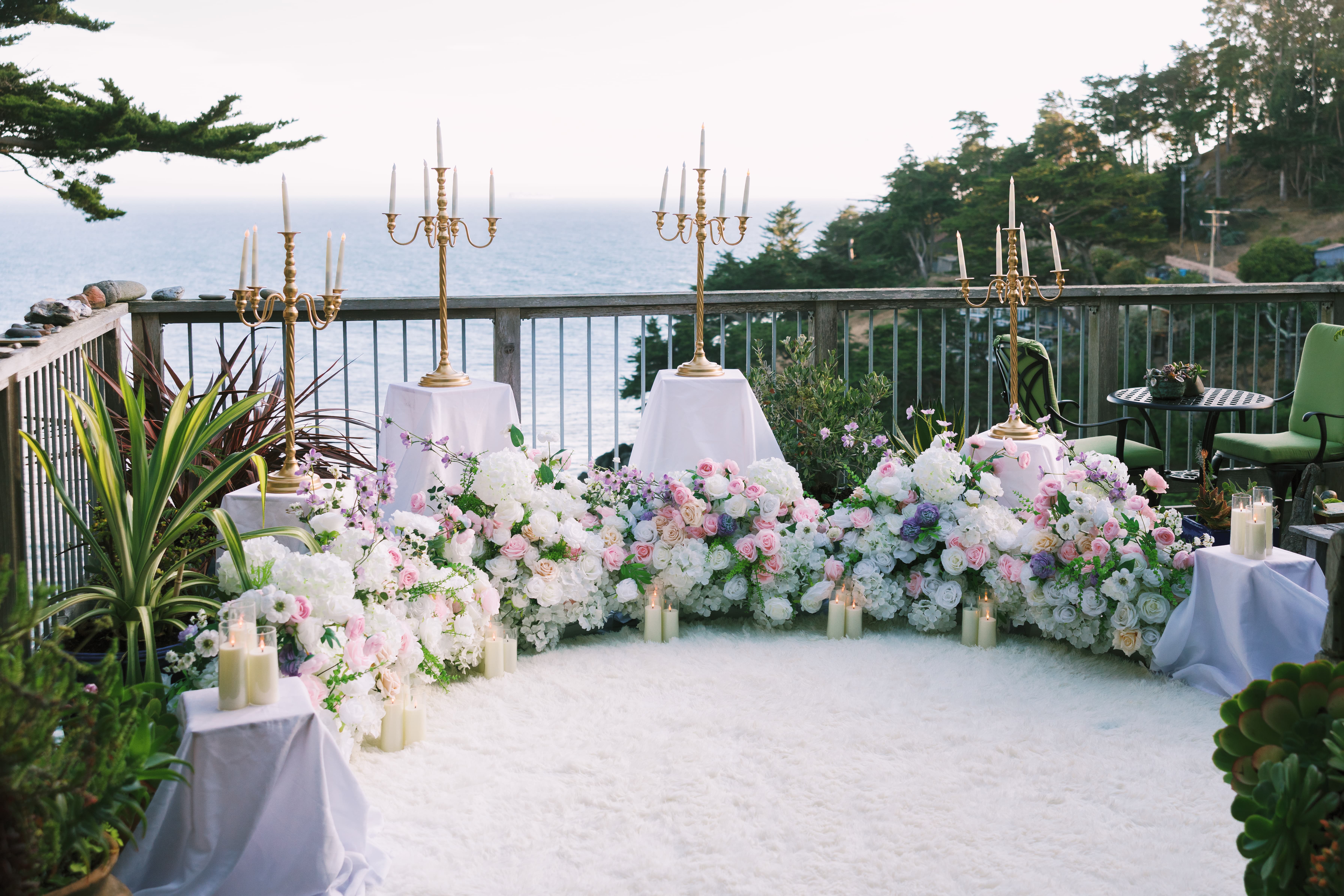 The Enchanted Romance &ndash; gold candelabras and a sweeping white, pink, and lavender floral arc on a fluffy white rug at an ocean overlook