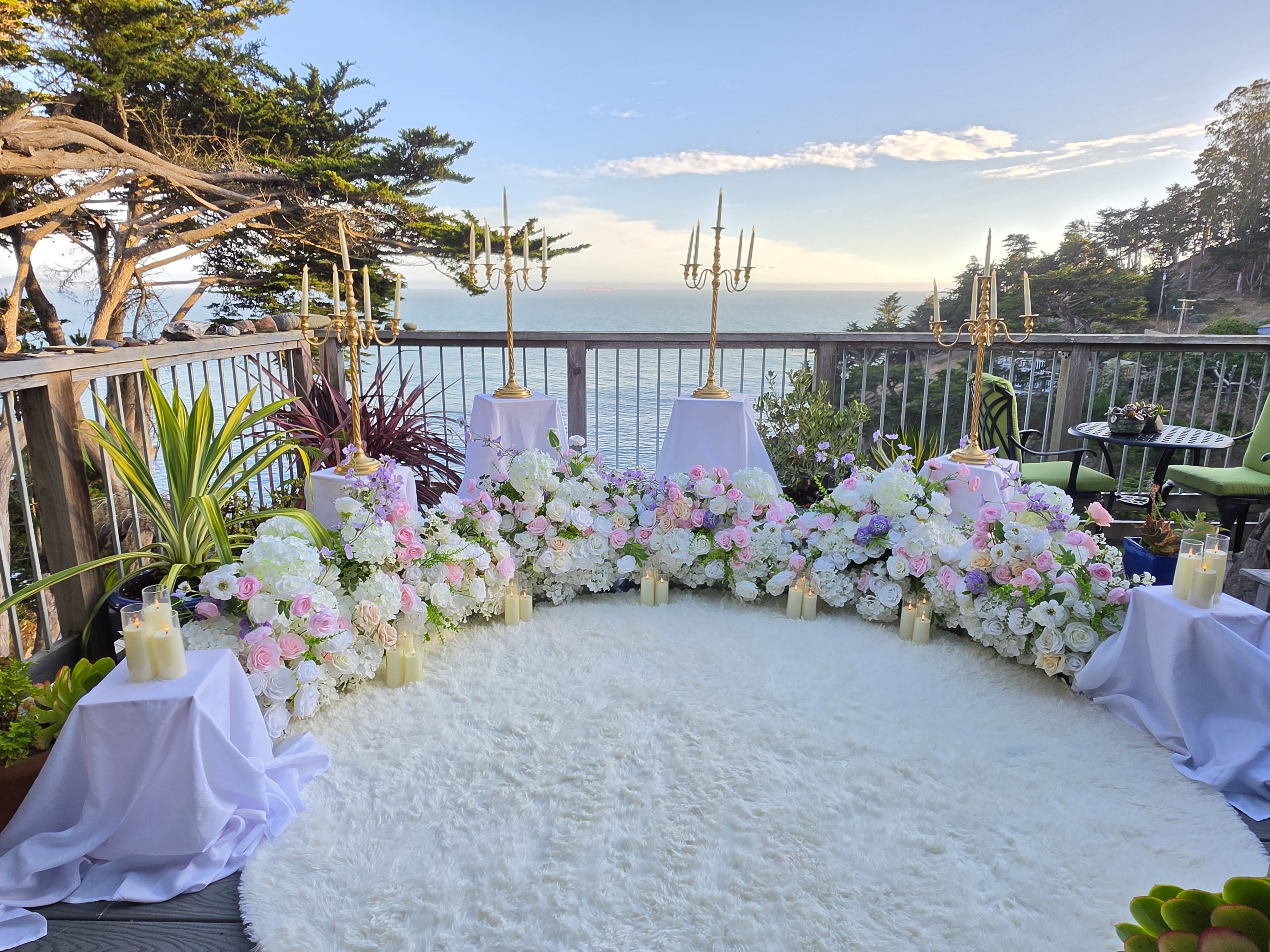 The Enchanted Romance &ndash; candlelit floral setup with gold candelabras on a North Bay Airbnb deck overlooking the water at sunset