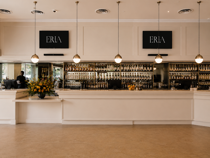 Full bar with brass pendant lighting and fresh floral arrangement inside ERIA Marina