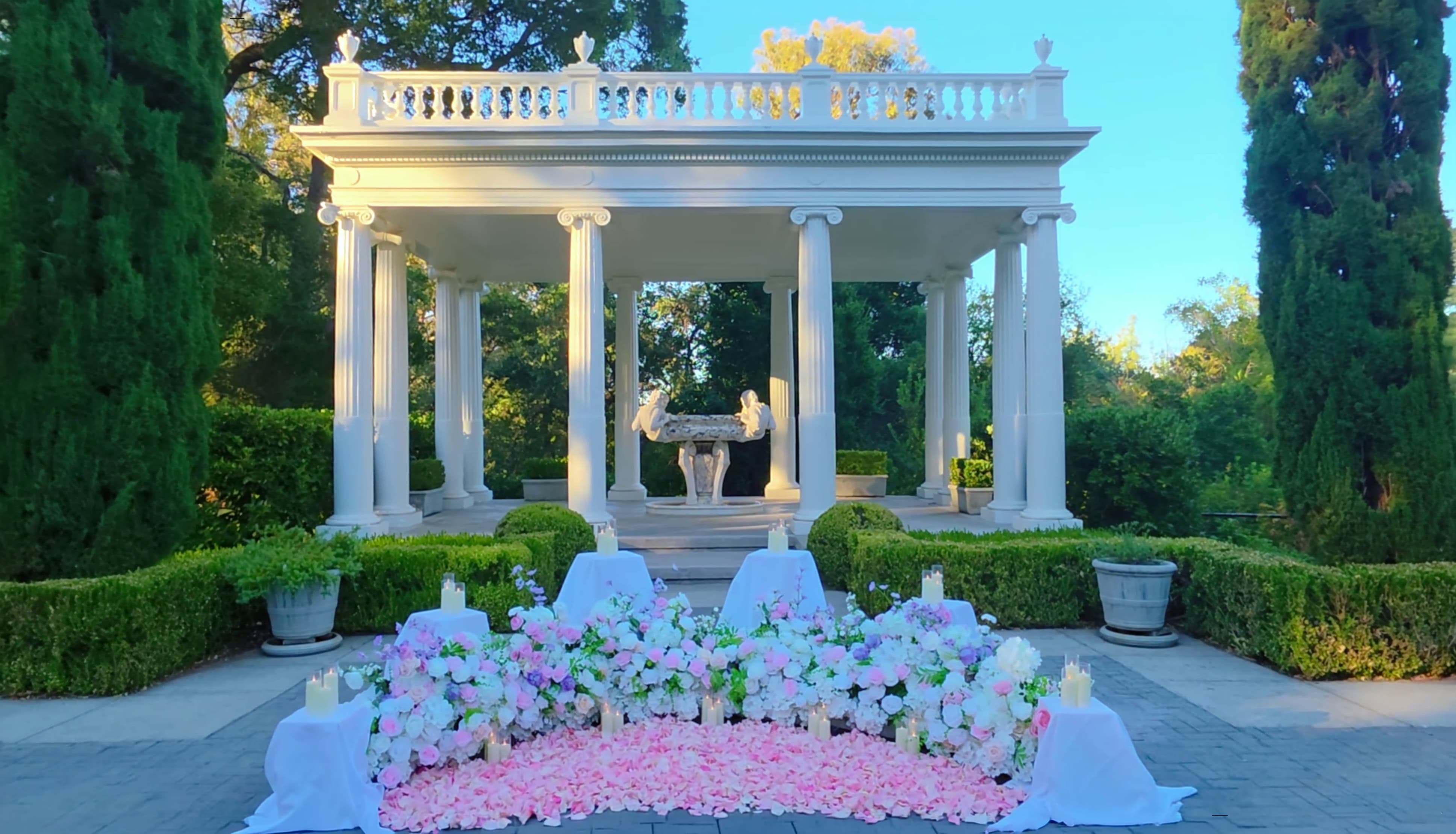 Golden hour view of the Love Temple at Montalvo Arts Center with a pink and white floral installation and rose petal aisle