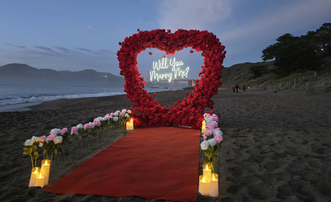 San Francisco Bay Area Baker Beach proposal with red heart arch and white/pink rose aisle way